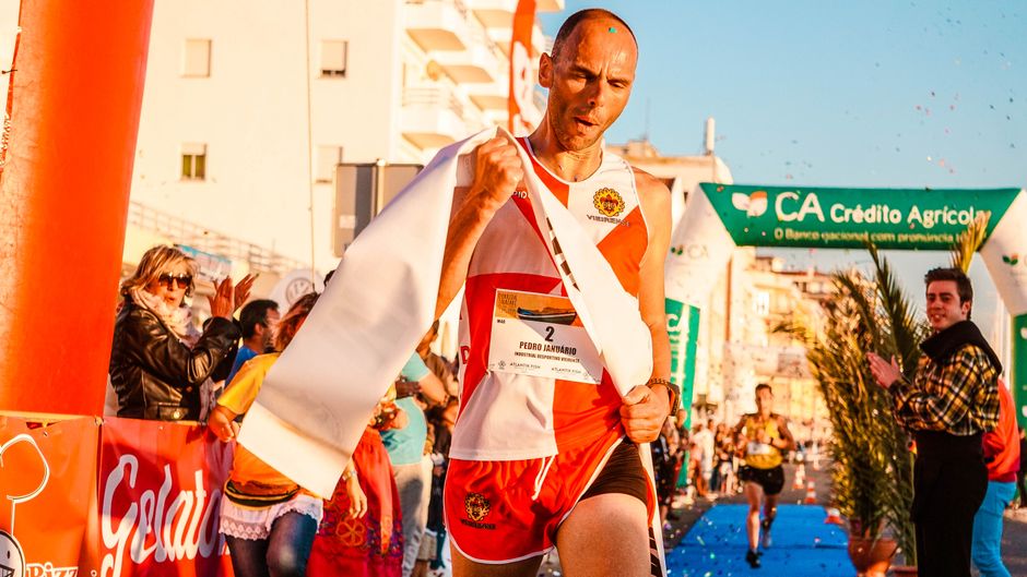 Male runner crosses finish line triumphantly in vibrant outdoor marathon event.